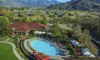 a large resort with a pool surrounded by lounge chairs and umbrellas , set against the backdrop of mountains at Pala Casino Spa and Resort