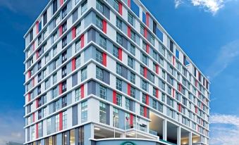 a modern , multi - story building with red and white facade , situated in a bustling city area at Kip Hotel