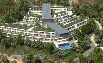 a large building with a green roof is surrounded by trees and has a swimming pool in the middle at Monchique Resort - Activities Included