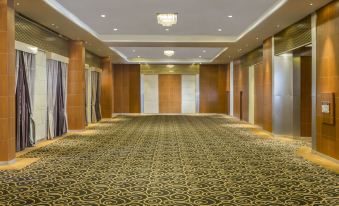 a long , empty conference room with wooden walls and a carpeted floor , illuminated by lights at Swiss-Belhotel Bogor