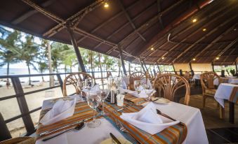 a dining room with a table set for a meal , complete with chairs and silverware at Amani Tiwi Beach Resort