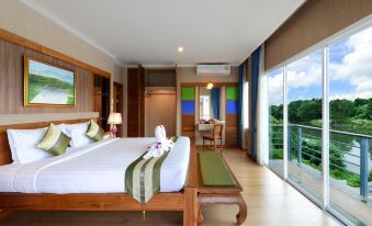 a spacious bedroom with a large bed , a dining table , and a view of the ocean at Princess River Kwai Hotel