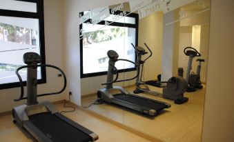 a well - equipped gym with various exercise equipment , including treadmills and weight machines , in a well - lit room at Hotel Milano
