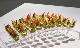 a row of small , clear trays filled with a variety of appetizers , such as shrimp and vegetables , placed on a white surface at Novotel Montreal Center
