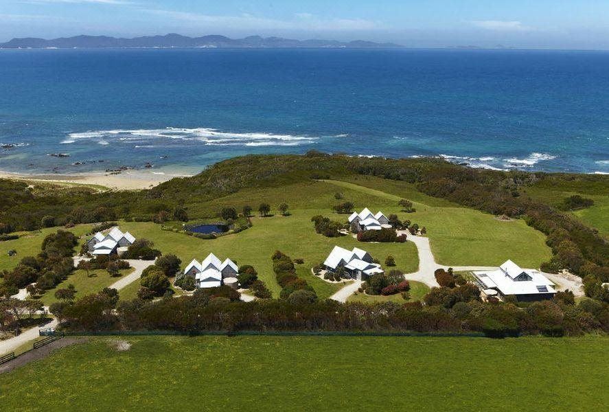 a bird 's eye view of a resort with houses , a golf course , and the ocean in the background at Bear Gully Coastal Cottages
