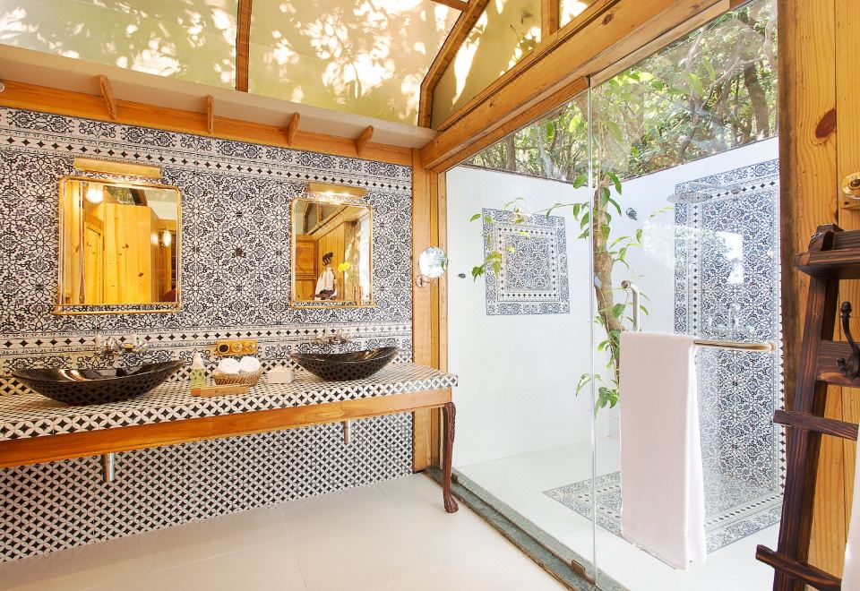 a bathroom with black and white tiled walls , a glass shower enclosure , and wooden benches at The Machan