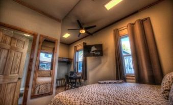 a bedroom with a bed , a desk , and a television mounted on the wall above the bed at The Cannery Lodge