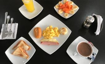a dining table with a variety of breakfast items , including eggs , toast , fruit , and coffee at Hotel Metropolitano