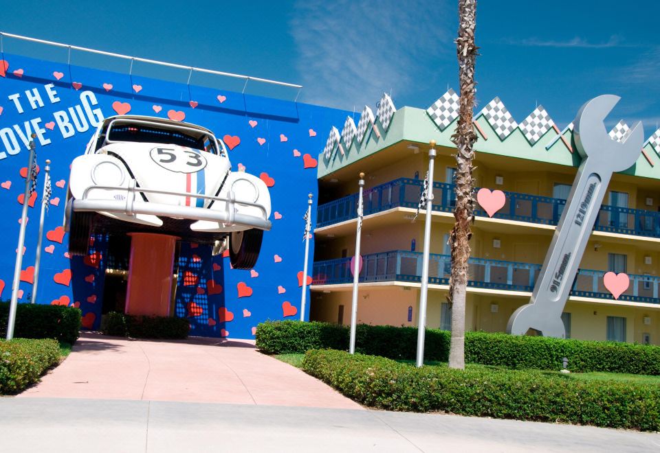a cartoonish volkswagen beetle car parked on the side of a building , with a heart decoration on its roof at Disney's All-Star Movies Resort