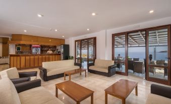 a spacious living room with wooden furniture , including couches , chairs , and a coffee table , arranged around the room at Lena Beach Hotel