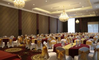 a large banquet hall with numerous dining tables covered in white tablecloths and adorned with red and gold napkins at Java Palace Hotel