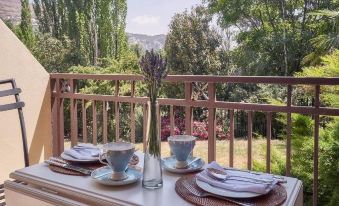 a table set with plates , cups , and napkins is situated on a balcony overlooking a mountainous landscape at Upper House Guesthouse