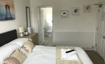 a well - organized bedroom with a white bed , towels , and other items , as well as an open doorway leading to a bathroom at Stanley Arms Hotel