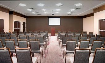 a conference room with rows of chairs arranged in a semicircle , and a projector screen on the wall at Courtyard Lufkin