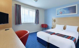 a hotel room with a blue and white theme , featuring a double bed , a chair , and a desk at Travelodge Southport