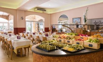 a large , well - lit dining room with a variety of fruits and vegetables displayed on the buffet table at Htop Caleta Palace #HtopBliss