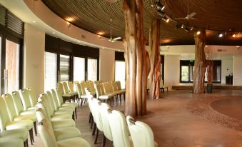a conference room with rows of chairs and a wooden ceiling , surrounded by large trees at Nayara Hangaroa