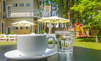 a cup of coffee is sitting on a dining table in front of an umbrella - covered chair , surrounded by outdoor furniture at Glenferrie Lodge