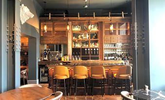 a bar with a wooden counter and chairs , surrounded by shelves filled with bottles and glasses at Angel Hotel