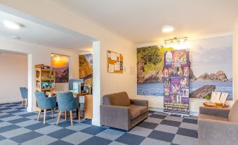 a room with a couch , chairs , and a dining table has a checkered floor and paintings on the wall at North Devon Resort