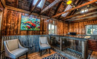 a room with wooden walls and ceiling , two chairs , a rug , and a painting on the wall at The Cannery Lodge