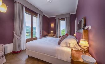 a large bed with white linens is situated in a bedroom with purple walls and wooden floors , next to a window at Albergo Posta Marcucci