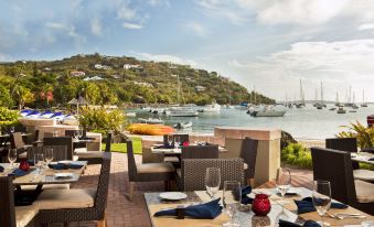 a restaurant with outdoor seating , tables , and chairs is situated on a wooden deck overlooking the water at The Westin St. John Resort Villas