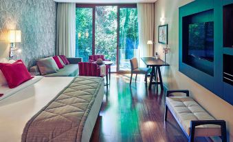a modern hotel room with a large bed , couch , dining table , and sliding glass doors leading to an outdoor terrace at Mercure Iguazu Hotel Iru