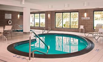 an indoor swimming pool with a diving board , surrounded by windows that let in natural light at Courtyard Newburgh Stewart Airport