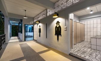 a hallway with a series of images on the wall and a person 's figure as well as a hat above the entrance at KS Hotel