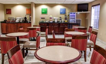 a large dining area with several tables and chairs , a counter with bowls and cups , and a microwave at Comfort Suites Gadsden Attalla