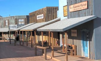 a wooden building with multiple benches and tables in front of it , surrounded by other buildings at Tombstone Monument Guest Ranch