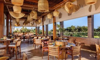 a large dining room with wooden tables and chairs , along with a view of the outdoors at NissiBlu Beach Resort