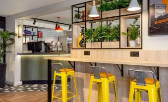a modern kitchen with yellow stools and a plant display , creating a fresh and inviting atmosphere at Super 8 by Wyndham Chester East