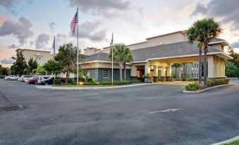 a large building with a parking lot in front of it , surrounded by palm trees at Homewood Suites by Hilton Tampa-Port Richey