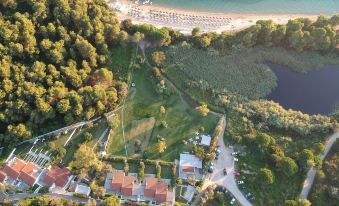 an aerial view of a beachside resort with multiple buildings , green grass , and a sandy beach at Skiathos Holidays Suites & Villas