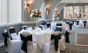 a beautifully decorated banquet hall with several round tables covered in white tablecloths and adorned with black and white chairs at The Kenilworth