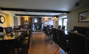 a dining room with wooden floors , black chairs , and a fireplace , creating a warm and inviting atmosphere at The Punchbowl Hotel