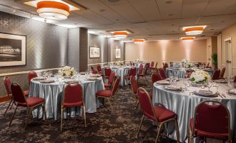 a large , empty banquet hall with red chairs and white tablecloths set up for a formal event at DoubleTree Suites by Hilton Minneapolis