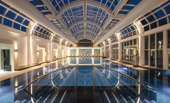 a large , modern swimming pool with a glass roof and white walls , illuminated by lights at Four Seasons Hotel Hampshire