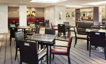 a large dining area with multiple tables and chairs arranged in an orderly fashion , possibly for a restaurant or cafe at Holiday Inn Express Northampton - South