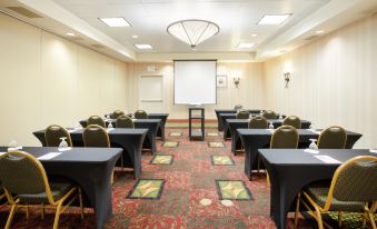 a conference room with rows of tables and chairs , a projector screen , and a rug at Hilton Garden Inn Casper