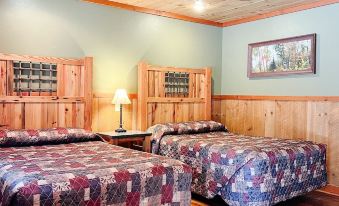a cozy wooden cabin with two beds , each bed having a quilt and a lamp at Cranberry Inn