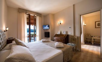 a bedroom with a bed , dresser , and tv , overlooking a balcony with wooden furniture and large windows at Hotel Duomo