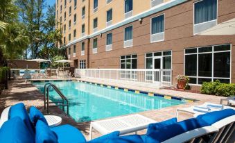 a large swimming pool with blue and white chairs is located in front of a building at Hampton Inn Hallandale Beach-Aventura