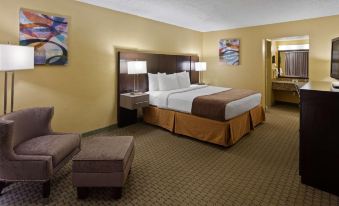 a large bed with white linens and a brown blanket is in the middle of a room at Ramada by Wyndham Cocoa