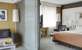 a modern hotel room with a large bed , tv , and desk , along with a desk and chair at Steigenberger Airport Hotel Amsterdam