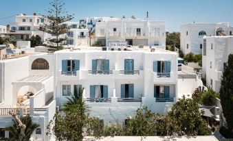a white building with blue shutters and balconies , situated on a hillside in a coastal town at Hotel Iris
