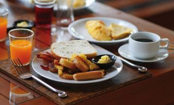 a wooden dining table with a plate of food , including hot dogs , french fries , and bacon at Oxford Suites Pendleton