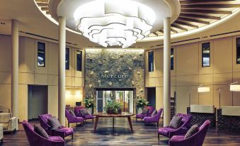 a modern lounge area with purple chairs and a stone ceiling features a large chandelier at Mercure Iguazu Hotel Iru